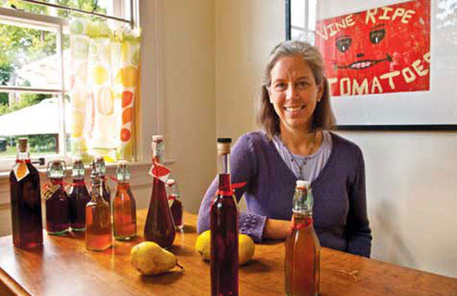 Susan Hamilton at table with her fruit infused bourbon cordials in bottles